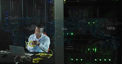 Coiling IT technician in light blue shirt at data center, with yellow Ethernet Stock Photos