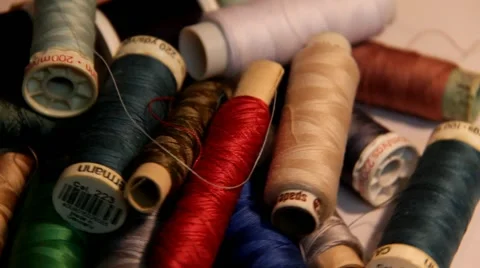 Coils and bobbins with colored thread, scattered on a white table Stock Footage 44326309