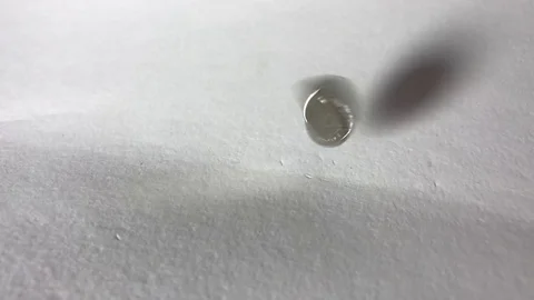 Coin falls on a white sheet of paper. Slow motion Video stock 111180513