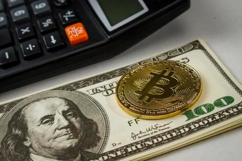 Coin in the form of bitcoin on a stack of dollar bills near the calculator Stock Photos