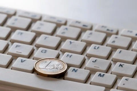 Coin in one Euro on the computer keyboard close-up. Online sales business con Stock Photos