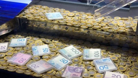 A coin pusher machine game full of gold coins and stacked banknote blocks in a Stock Footage 345973347