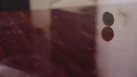 The coin is spinning on the glossy table surface Stock Footage 141921023