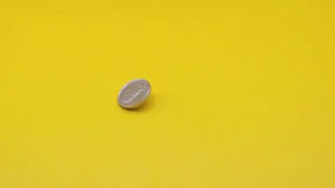The coin is spinning on a yellow surface Stock Footage 333915101
