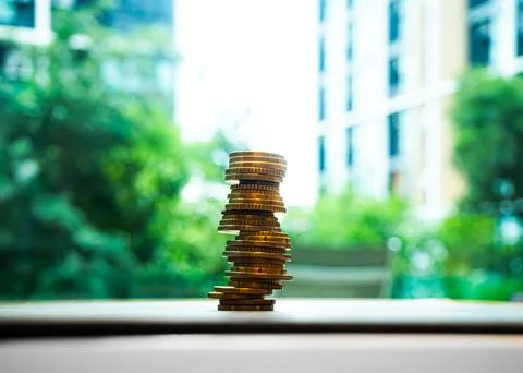 Coin stack on blur nature growth tree and building, business finance Stock Photos