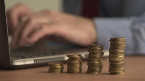 Coin stack with businessman using laptop computer in background 動画素材 89208706