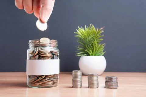 The coins are stored in a glass jar to accumulate finances. Stock Photos