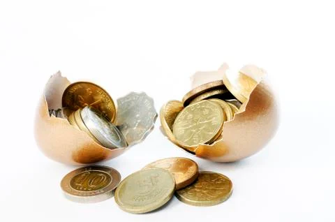 Coins in broken golden eggshell Stock Photos