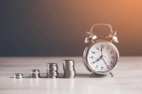 Coins with clock on table Stock Photos