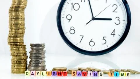 Coins with clock on white table. Summer Daylight Saving Time (DST). Turn time Stock Photos
