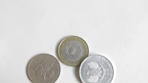 Coins from different countries around the world are tossed over a white surface Stock Footage 167294430