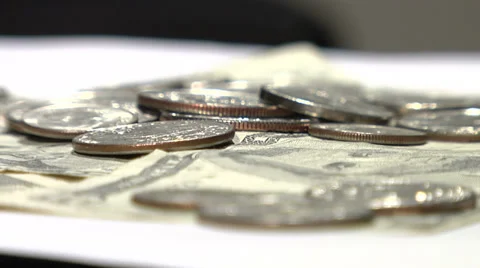 Coins fall onto rotating turntable with dollar bills Video stock 35769405