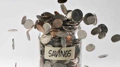 Coins falling into a coin jar in slow motion. Stockbeeldmateriaal 311606750