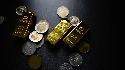 Coins falling onto gold bars in slow motion representing wealth and investment Stock Footage 331121359
