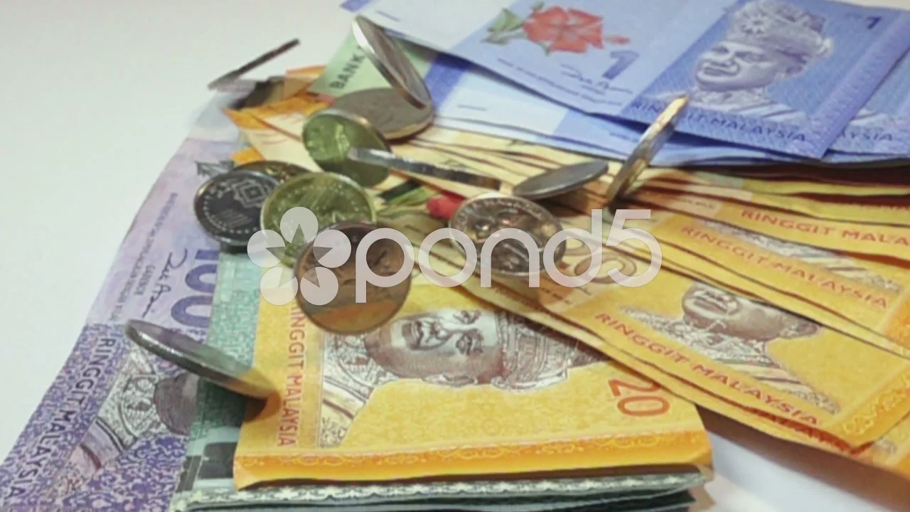 Coins falling on Malaysia Ringgit Notes on white background