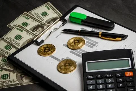 Coins in the form of bitcoin with a calculator on the sheets with statistics Stock Photos