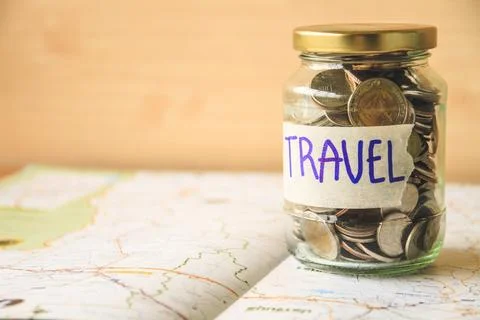 Coins in a glass jar on a map. Saving money for travel concept Stock Photos