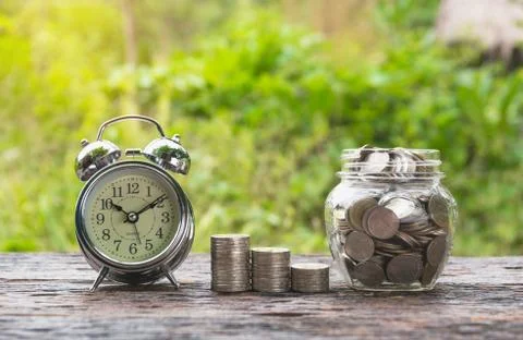 Coins in jar with money stack step growing money and alarm clock, Concept fin Stock Photos