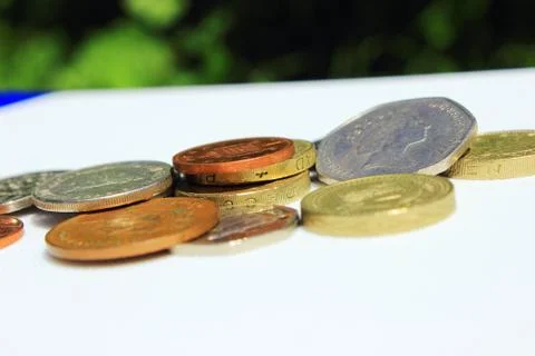 Coins from the side lying on white surface Stock Photos