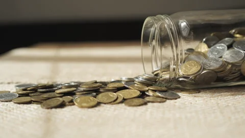 Coins Spilling From Glass Jar Representing Personal Savings Concept Stock Footage 346034478