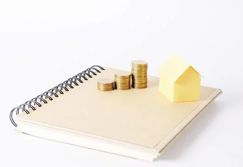 Coins stack and yellow house model on book for mortgage loan Stock Photos