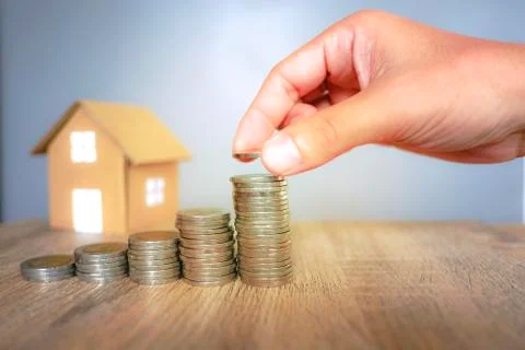 Coins stack with human hand and paper house background for saving Stock Photos