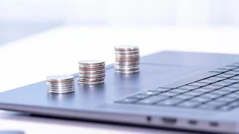 Coins stack on laptop computer in office. Concept of finance and investment Stock Photos