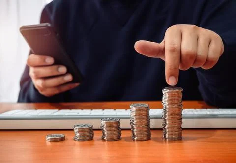 Coins stacked as bar graph chart steps pointing by person hand who holding .. Stock Photos