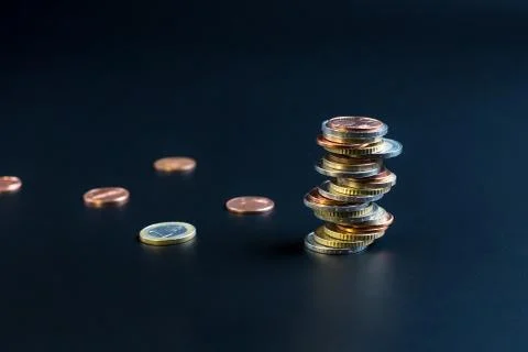 Coins stacked on each other in different positions on a black background Stock Photos