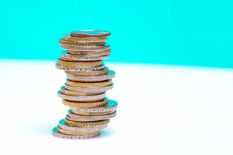 Coins stacked on each other in different positions on a blue and white backgr Stock Photos