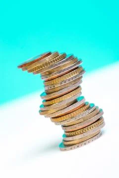 Coins stacked on each other in different positions on a blue and white backgr Stock Photos