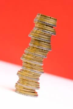 Coins stacked on each other in different positions on a red and white backgro Stock Photos