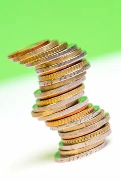 Coins stacked on each other in different positions on a green and white backg Stock Photos