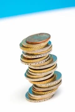 Coins stacked on each other in different positions on a blue and white backgr Stock Photos