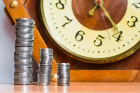 Coins on the table on the background of the clock Stock Photos