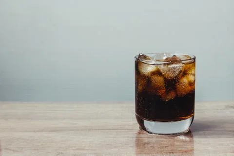 Cola and ice cube in clear glass on wooden table Stock Photos