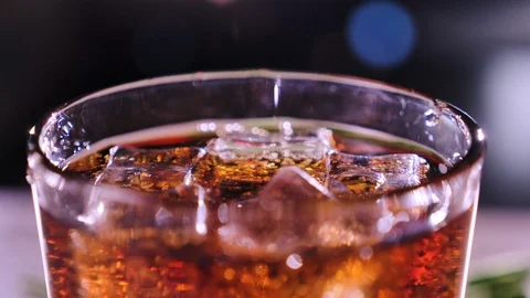 Cola with bubbles in glass. Ice cubes fall into a cup. Slow motion. Stock-Footage 120554729