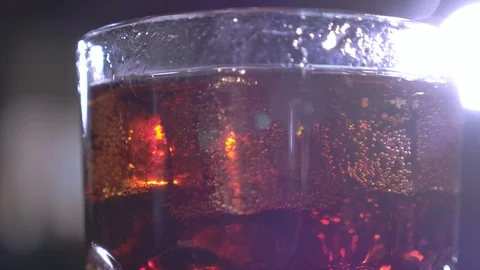 Cola with bubbles in glass. Ice cubes fall into a cup. Slow motion. Stock-Footage 120554873