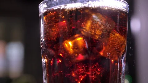 Cola with bubbles in glass. Ice cubes fall into a cup. Slow motion. Stock Footage 120554902