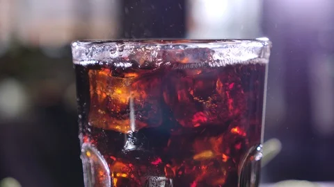 Cola with bubbles in glass. Ice cubes fall into a cup. Slow motion. Stock-Footage 120555035