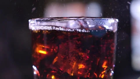 Cola with bubbles in glass. Ice cubes fall into a cup. Slow motion. Stock-Footage 120555061