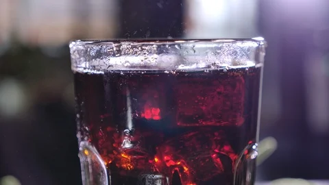 Cola with bubbles in glass. Ice cubes fall into a cup. Slow motion. Stock-Footage 120555237