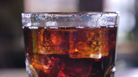 Cola with bubbles in glass. Ice cubes fall into a cup. Slow motion. Stock-Footage 120555500