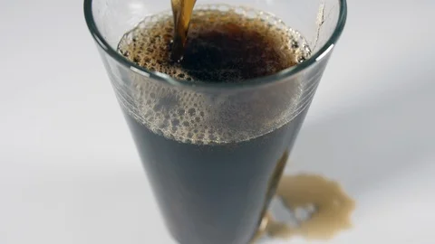 Cola fizzy liquid bubbles drink poured from above into a clear glass on a white Stock Footage 88513259