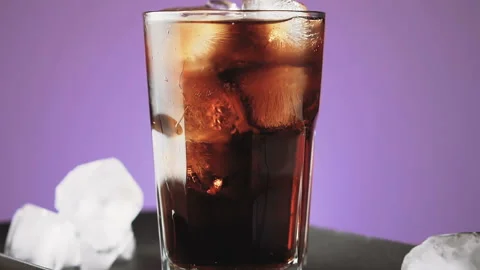 Cola with ice cubes and bubbles in glass, slow motion. Stock Footage 92322935