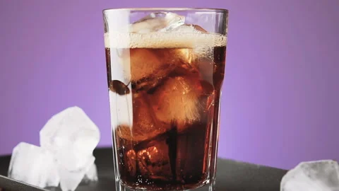 Cola with ice cubes and bubbles in glass, slow motion. Stock Footage 92323003