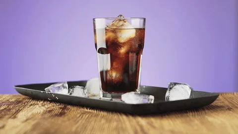 Cola with ice cubes and bubbles in glass, slow motion. Stock Footage 92323371