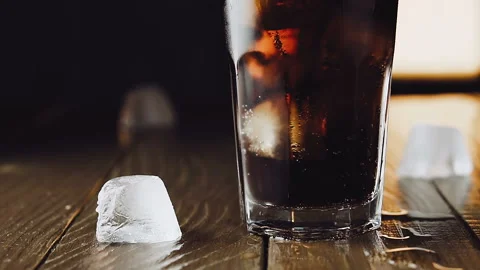 Cola with ice cubes and bubbles in glass, slow motion. Stock Footage 93041292