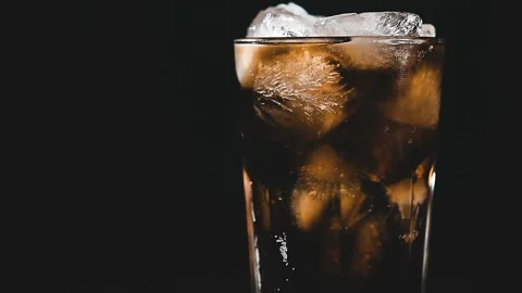 Cola with ice cubes and bubbles in glass, close-up, light moving. Stock Footage 93446842