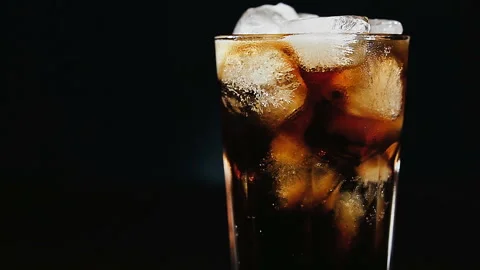 Cola with ice cubes and bubbles in glass, close-up, light moving. Stock Footage 93446887